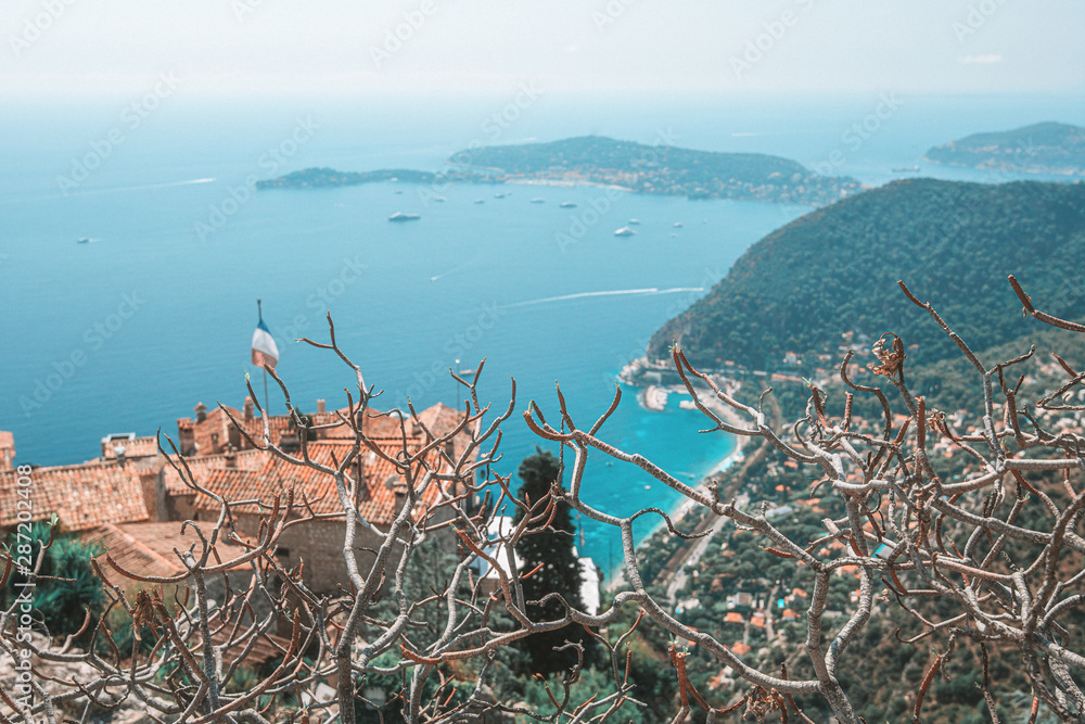 view on the Mediterranean Sea over the roofs of the picturesque medieval village of Eze with the Saint-Jean-Cap-Ferrat peninsula on the horizon