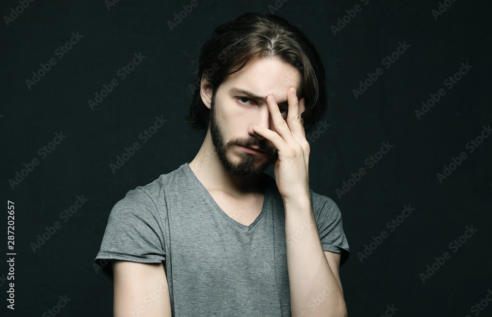 unhappy man touching his forehead over black background