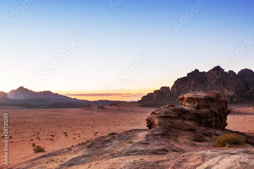 View of the sunset over the Wadi Rum desert in Jordan, with mountains in the background and blue yellow brown and red colors. Feeling of peace and tranquility.