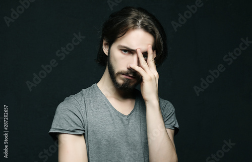 unhappy man touching his forehead over black background
