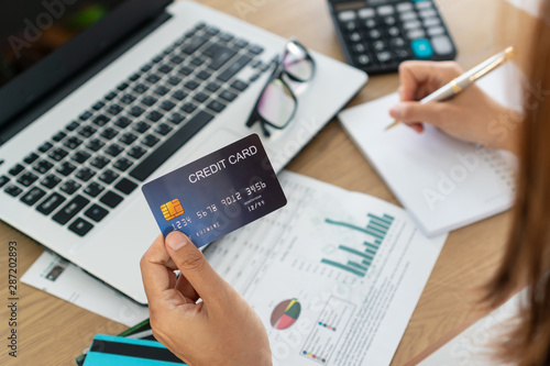 Woman holding credit card and writing , account and saving concept.