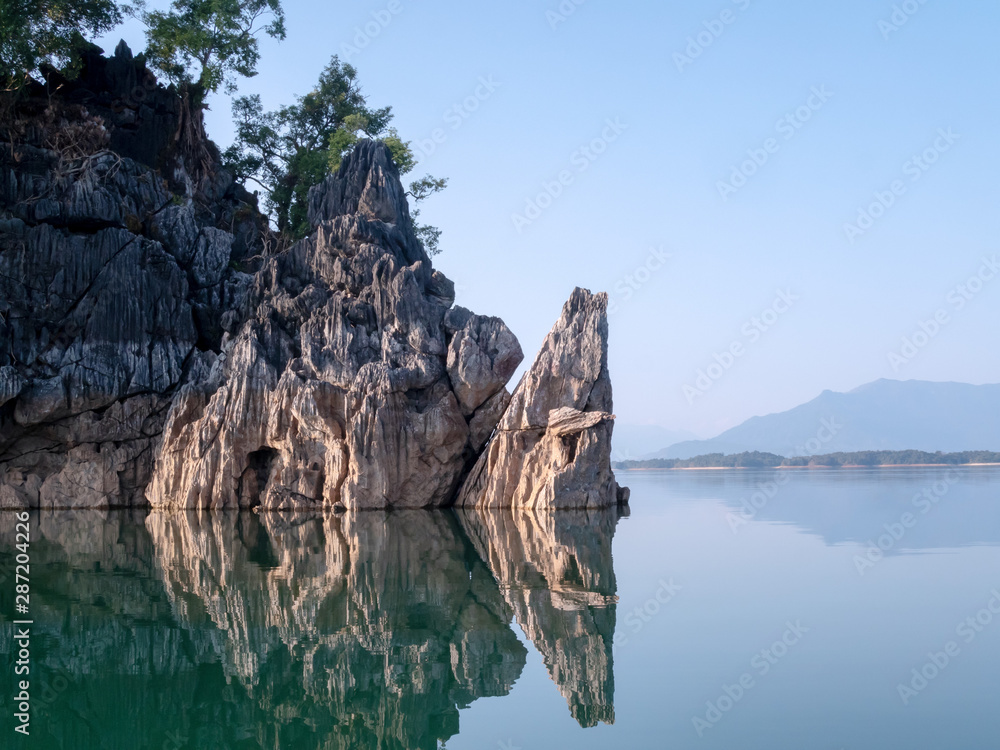 Rock mountain island reflect on lake water with clear blue sky. Calm and peace river.
