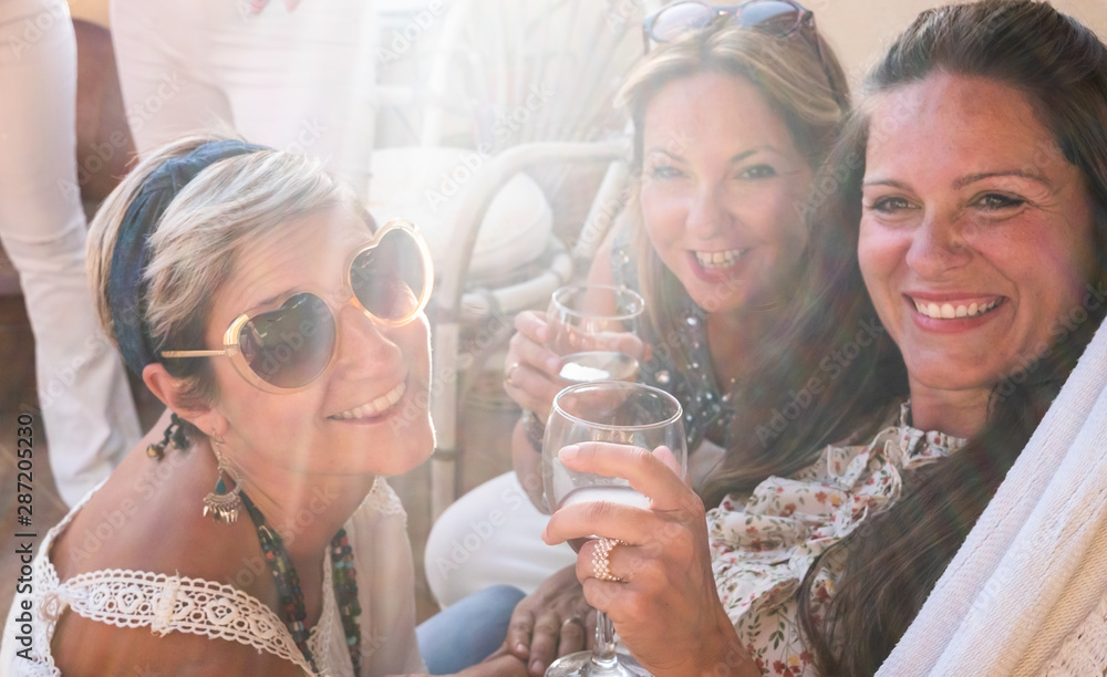 A group of females people in friendship enjoying a party on the terrace toasting with red wine. Beautiful women. Simplicity and happiness together