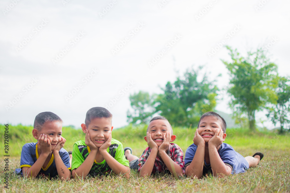 cute little boys lying on grass field and feeling happy, smile and happy together with friends, soft focus. cute little boys lying on grass field and feeling happy, smile and happy together with friends, soft focus.