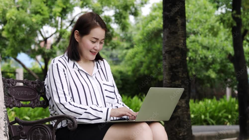 Business woman is typing text on the laptop keyboard to work or chat in public gardens. Business woman is typing text on the laptop keyboard to work or chat in public gardens.