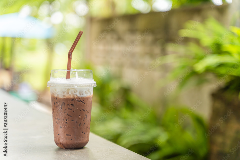 Iced chocolate topped with milk froth in a plastic cup with brown straw. Iced chocolate topped with milk froth in a plastic cup with brown straw.
