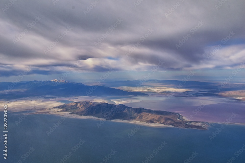 Great Salt Lake Utah Aerial view from airplane looking toward Oquirrh Mountains and Antelope Island, Tooele, Magna, with sweeping cloudscape. United States.