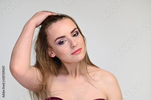 A close-up portrait of a cute girl  a young woman with beautiful curly hair on a white background with excellent face skin and outstanding fashionable make-up. Beauty  brightness.