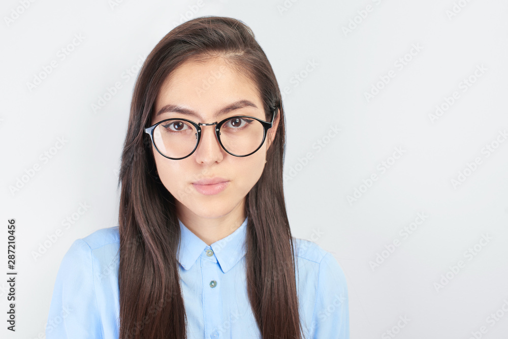 Horizontal portrait of modest Asian student girl with glasses, shirt  and long brunette hair. Kazakh schoolgirl looking at the camera on white background isolated, natural beauty