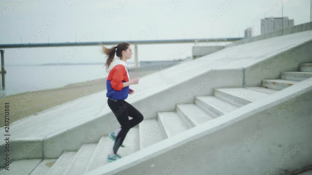 Young sporty woman running upstairs on city stairs.
