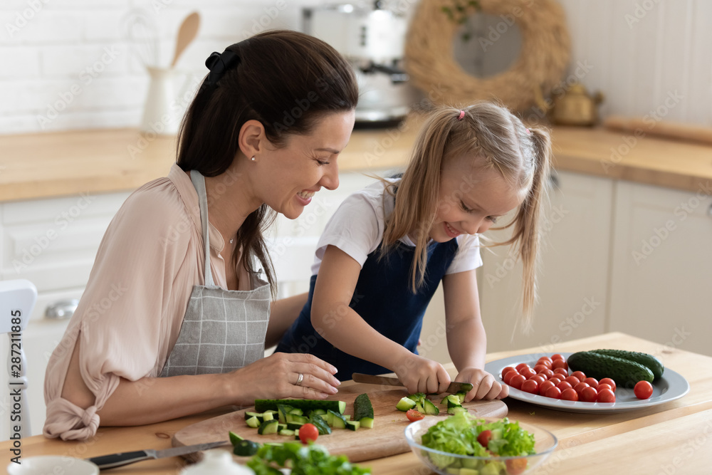 Mom teaches daughter to cook vegetable salad