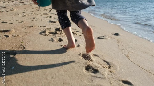 Caucasian girl feet running on the beach at sunset in slow motion - low angle shot