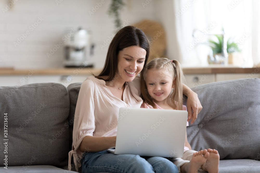 Young mother and preschooler daughter sitting on couch with notebook Young mother and preschooler daughter sitting on couch with notebook