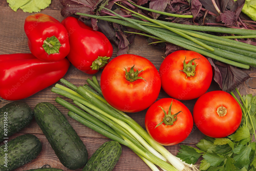 Summer vegetables and greens on a rustic wooden table