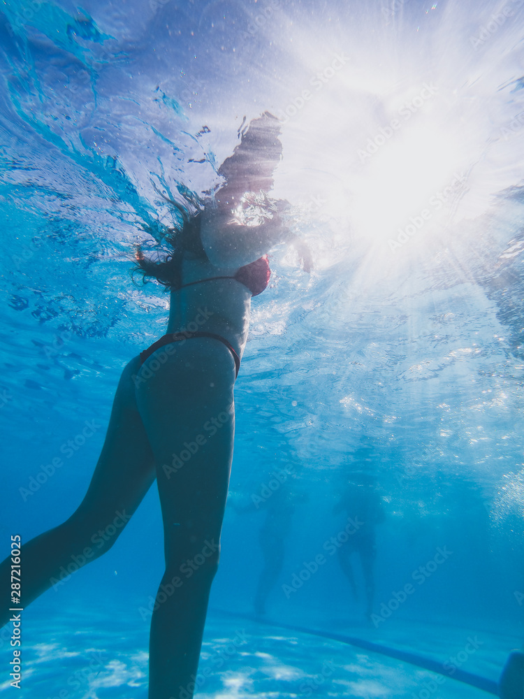 Underwater view from a girl with a red bikini in a pool
