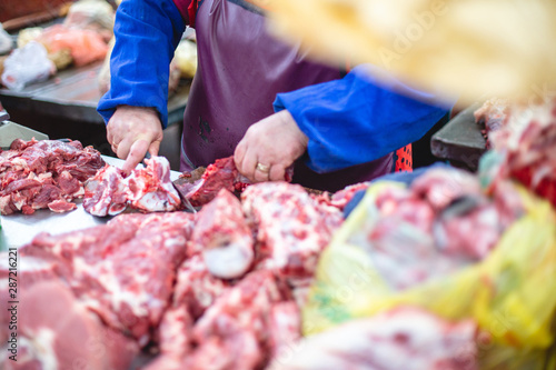 the shop assistant presents a piece of meat and cuts half of it for the buyer. selective focus photo from the natural home market with meat horned animals