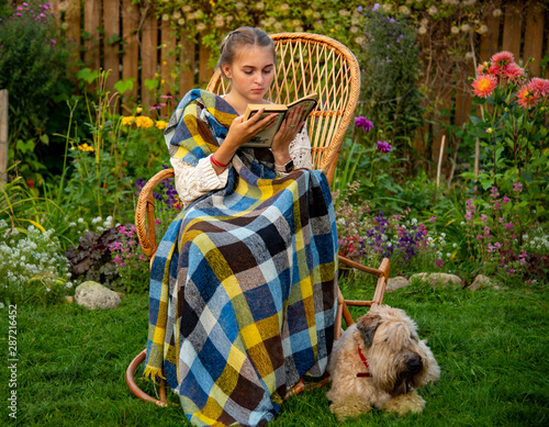Canvas Print Beautiful girl sitting in a wicker rocking chair with a book