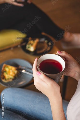 close up photo of  mug of tea and teapot in female hands. Two girlfriends drinking tea while chatting in a cafe