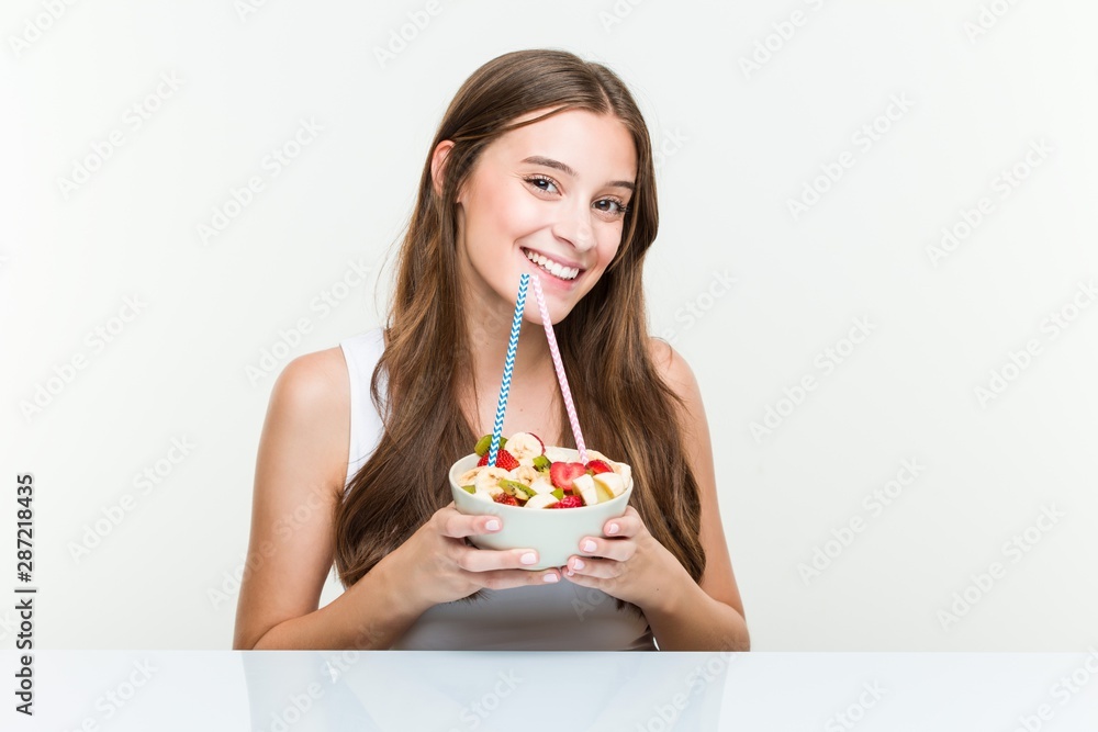 Young caucasian woman drinking a fruit bowl with a straw. Healthy life concept. Young caucasian woman drinking a fruit bowl with a straw. Healthy life concept.