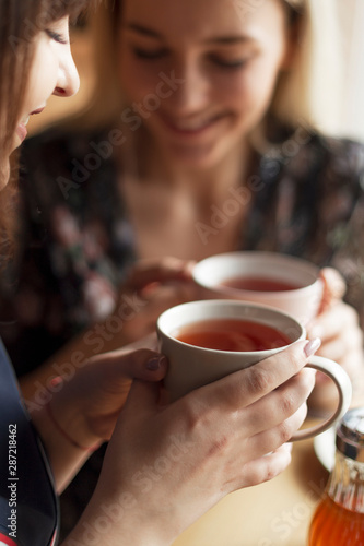 05.08.2019 Kyiv, Ukraine: two pretty women holding mugs of delicious hot tea, drinking and having fun talking