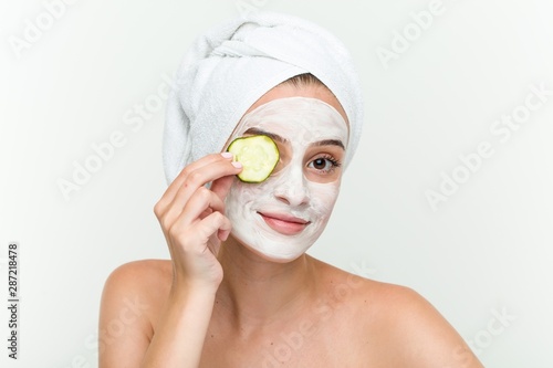 Young caucasian woman enjoying of a facial mask treatment with cucumber