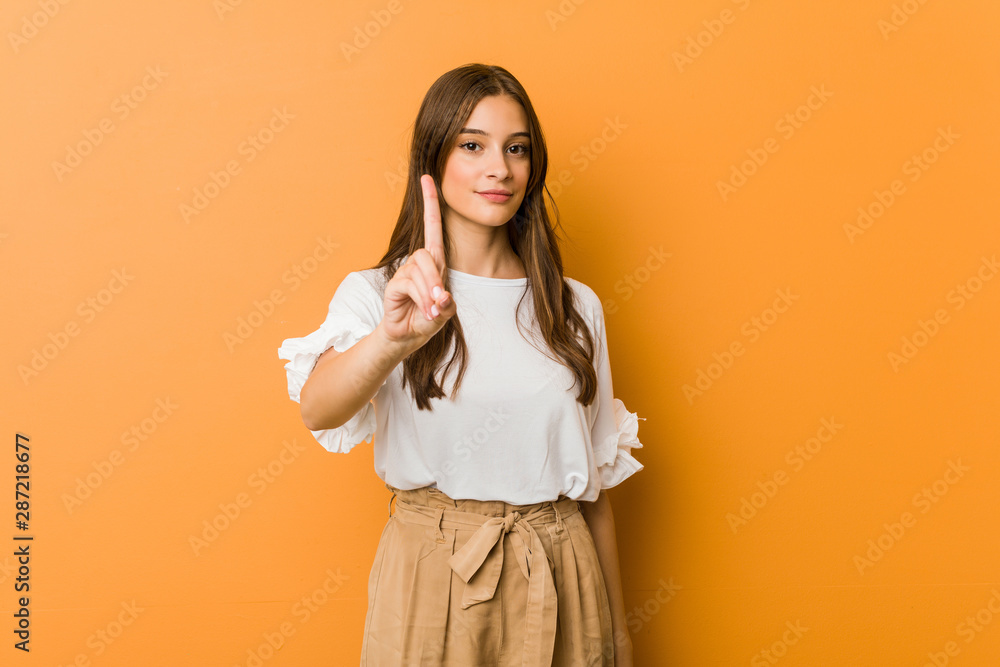 Young caucasian woman showing number one with finger. - obrazy, fototapety, plakaty 