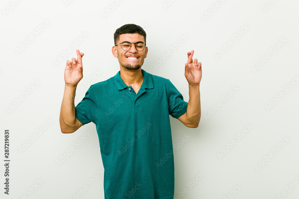 Young hispanic man crossing fingers for having luck Young hispanic man crossing fingers for having luck