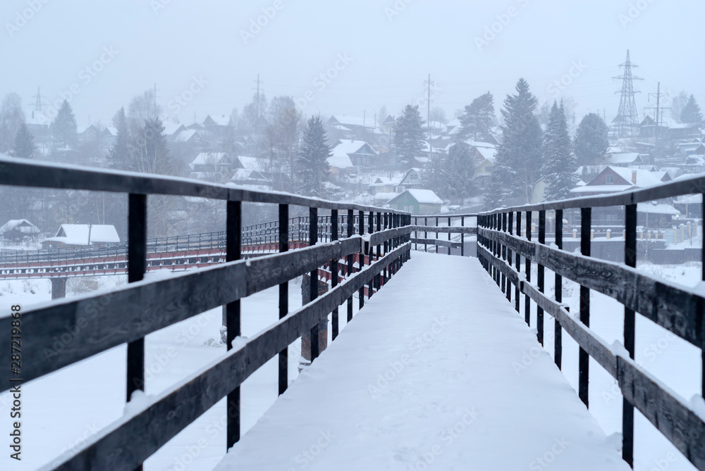 Naklejka premium snow-covered bridge over the river in the winter countryside