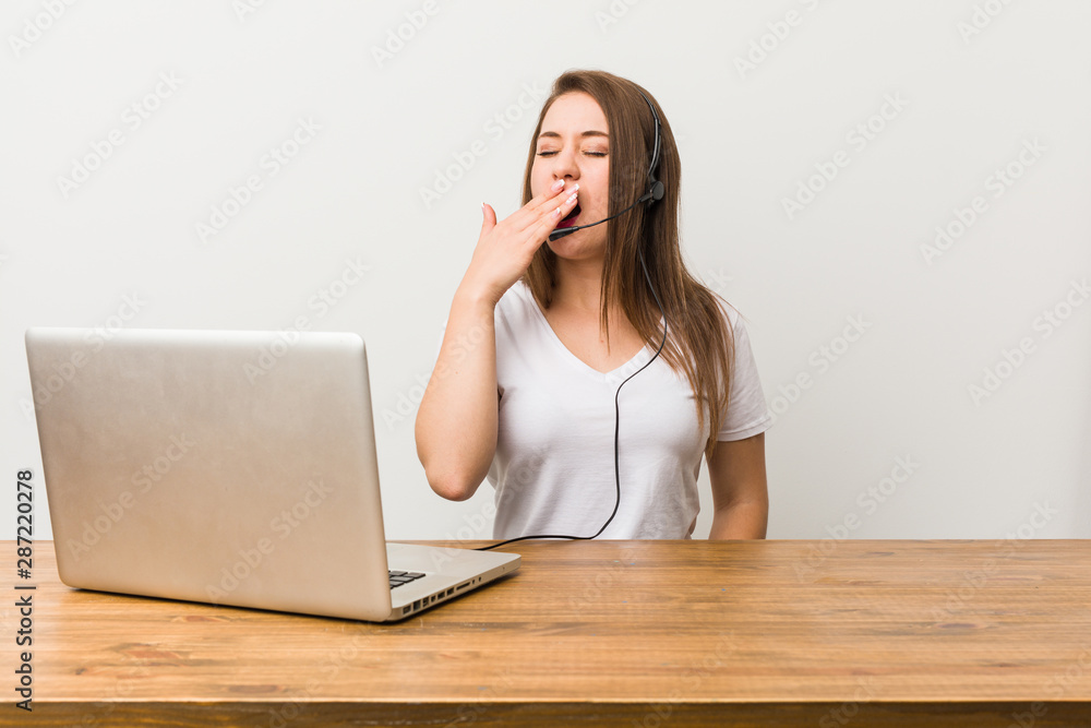 Young telemarketer woman yawning showing a tired gesture covering mouth with hand.