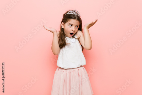 Little girl wearing a princess look surprised and shocked.