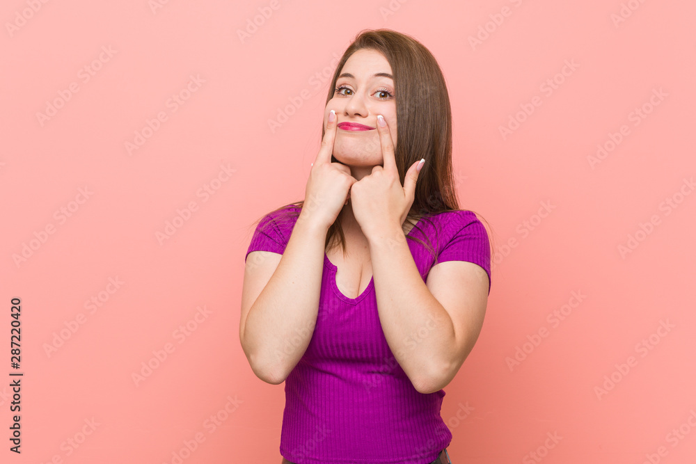 Young hispanic woman against a pink wall doubting between two options. Young hispanic woman against a pink wall doubting between two options.