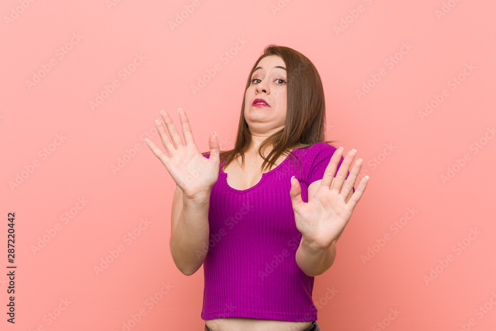 Young hispanic woman against a pink wall being shocked due to an imminent danger Young hispanic woman against a pink wall being shocked due to an imminent danger