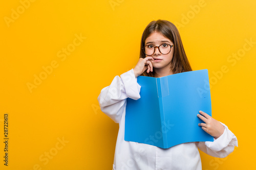 Little caucasian girl wearing a doctor costume biting fingernails, nervous and very anxious.