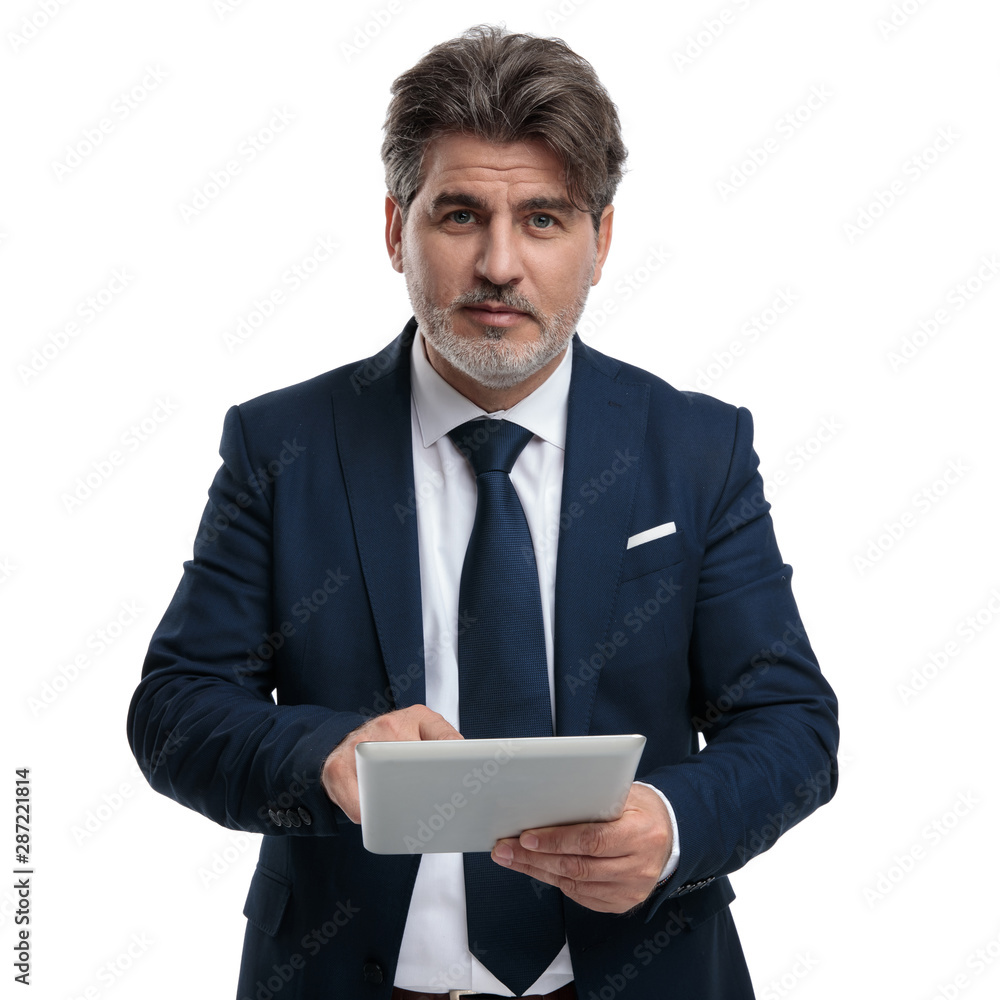 Optimistic businessman using his tablet and looking forward Optimistic businessman using his tablet and looking forward