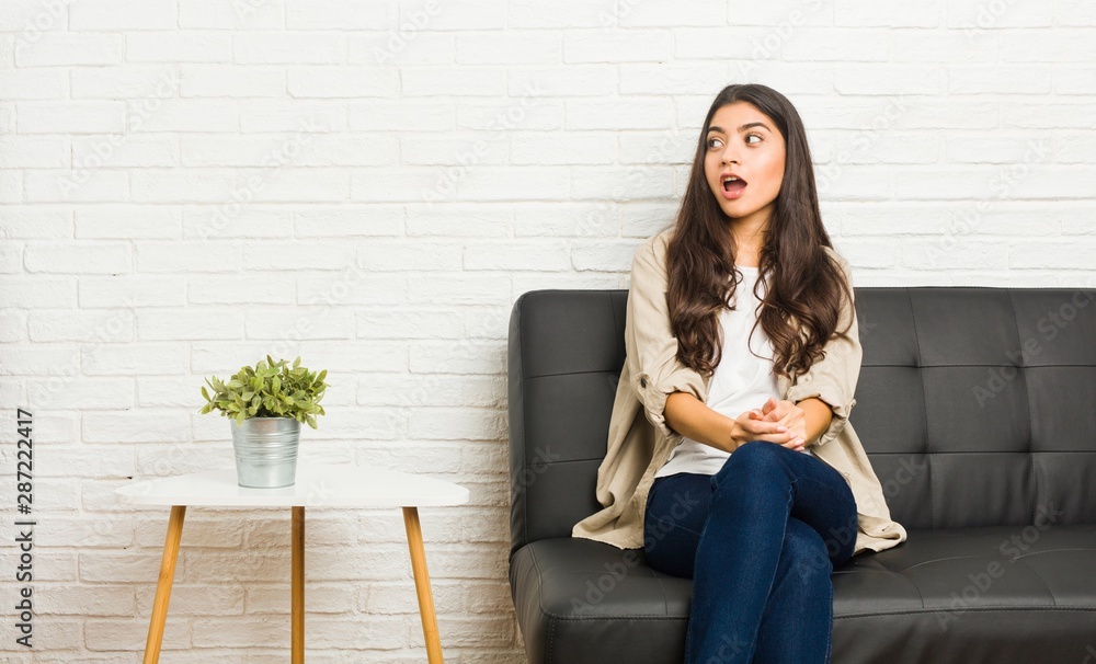Young arab woman sitting on the sofa being shocked because of something she has seen. Young arab woman sitting on the sofa being shocked because of something she has seen.