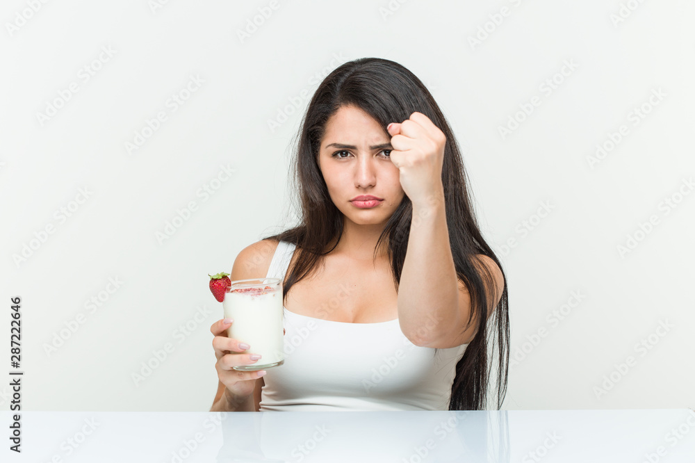 Young hispanic woman holding a smoothie young hispanic woman holding an avocado toast showing fist to camera, aggressive facial expression.< mixto > Young hispanic woman holding a smoothie young hispanic woman holding an avocado toast showing fist to camera, aggressive facial expression.< mixto >