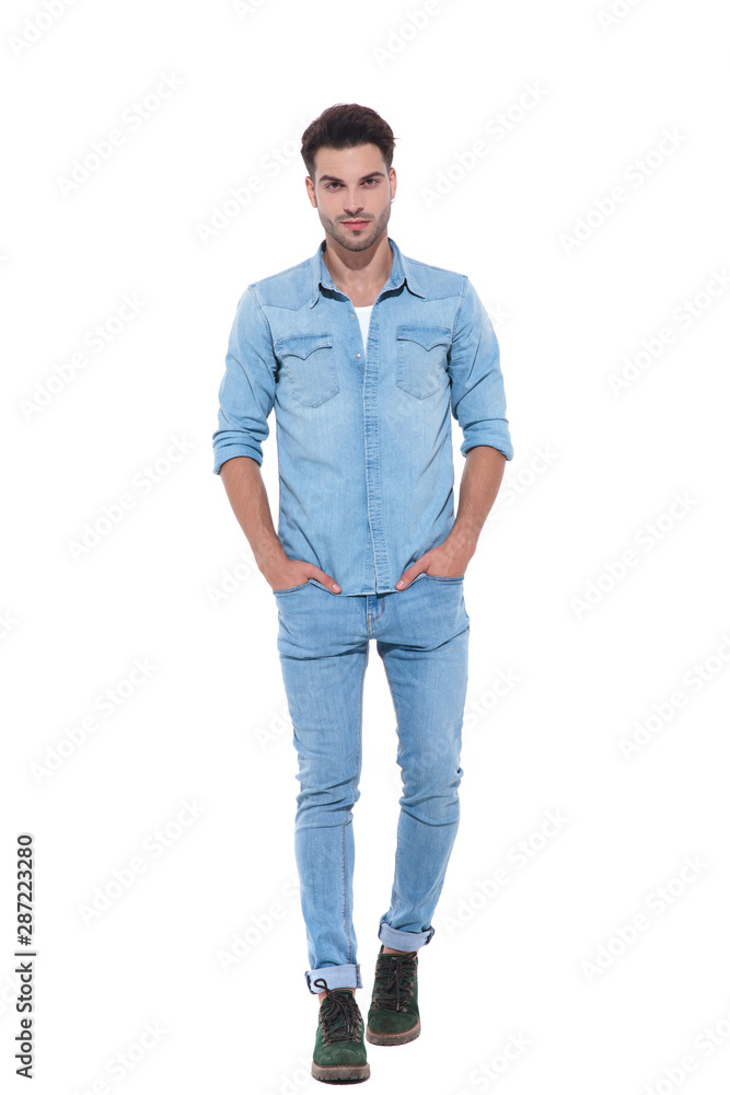 relaxed young man walking with hands in his pockets relaxed young man walking with hands in his pockets