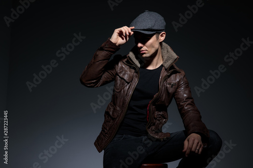 seated man fixing hat with nonchalant attitude