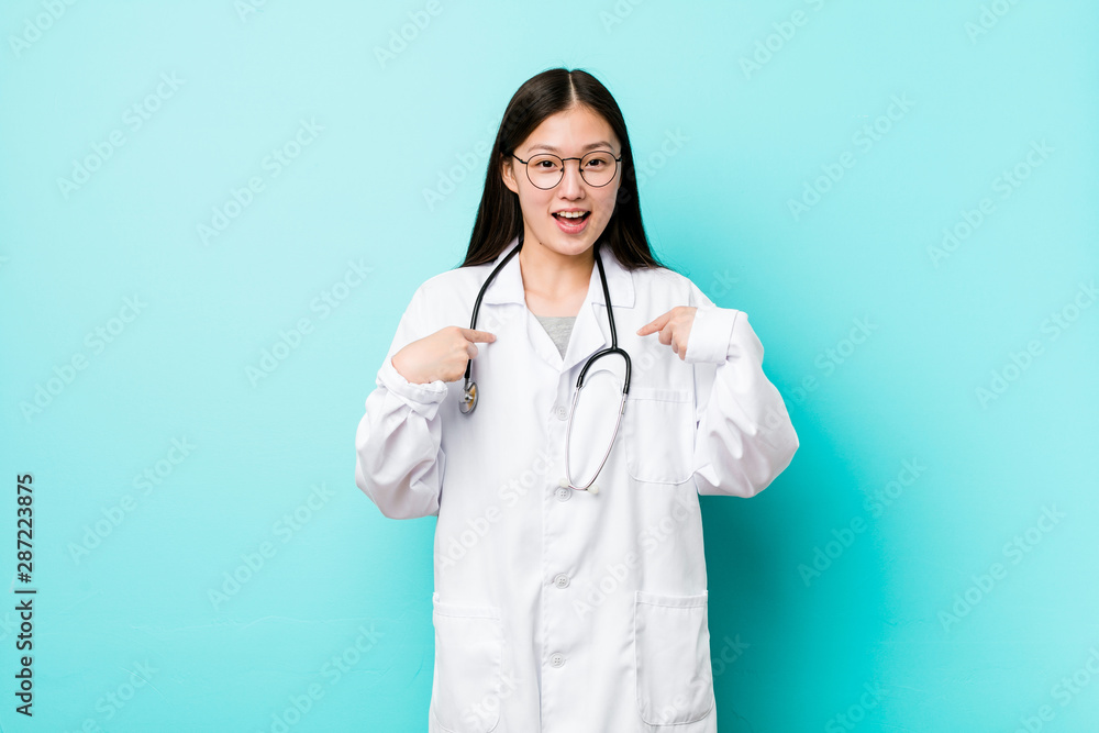 Young chinese doctor woman surprised pointing with finger, smiling broadly. Young chinese doctor woman surprised pointing with finger, smiling broadly.
