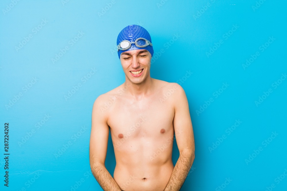 Young swimmer man laughs and closes eyes, feels relaxed and happy.