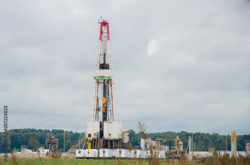Pump jack with a derrick drilling a new well in the background. Pump jack with a derrick drilling a new well in the background.