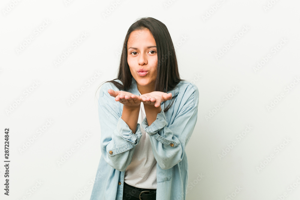 Young hispanic woman folding lips and holding palms to send air kiss. Young hispanic woman folding lips and holding palms to send air kiss.