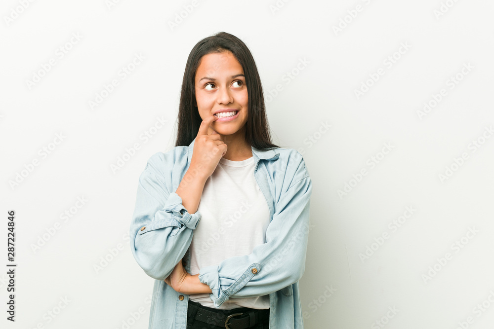 Young hispanic woman relaxed thinking about something looking at a copy space. Young hispanic woman relaxed thinking about something looking at a copy space.