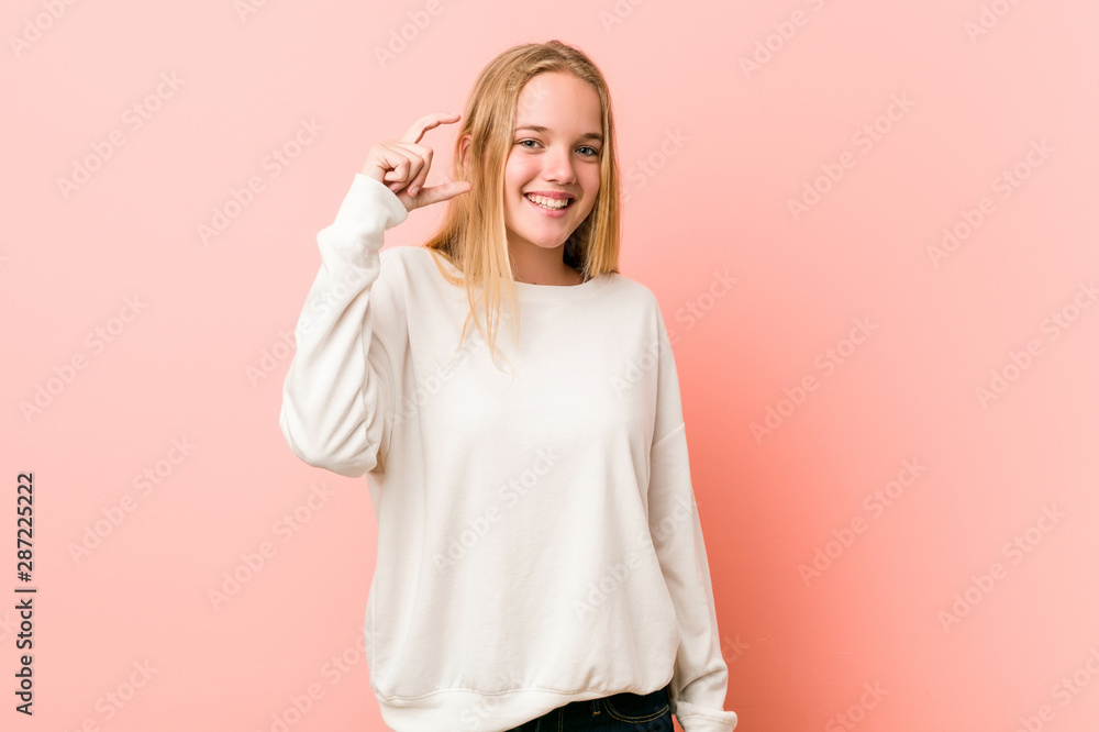 Young blonde teenager woman holding something little with forefingers, smiling and confident. Young blonde teenager woman holding something little with forefingers, smiling and confident.