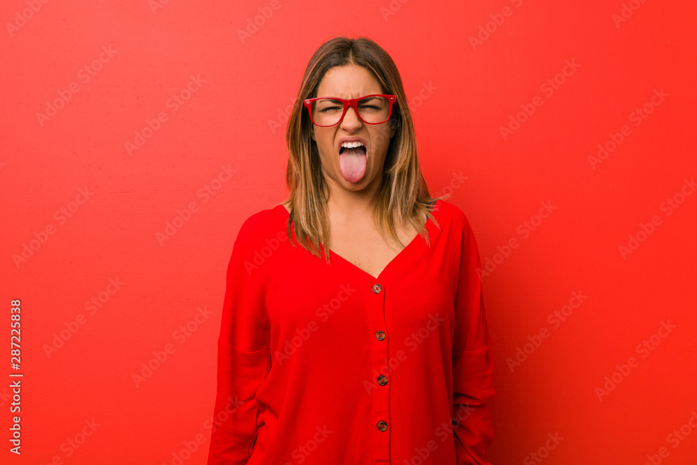Young authentic charismatic real people woman against a wall funny and friendly sticking out tongue. Young authentic charismatic real people woman against a wall funny and friendly sticking out tongue.