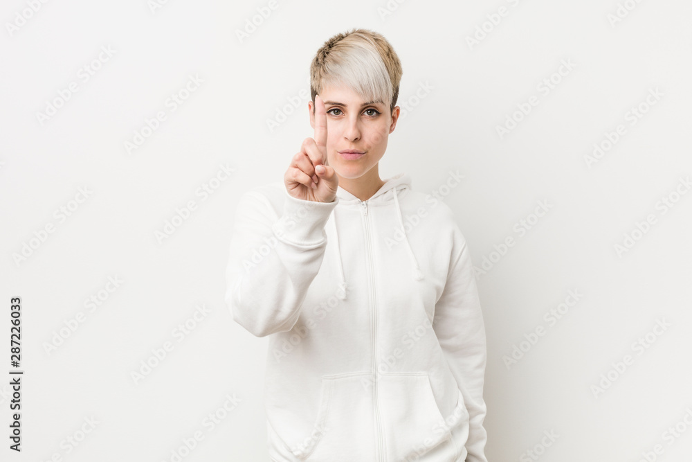 Young curvy woman wearing a white hoodie showing number one with finger. Young curvy woman wearing a white hoodie showing number one with finger.