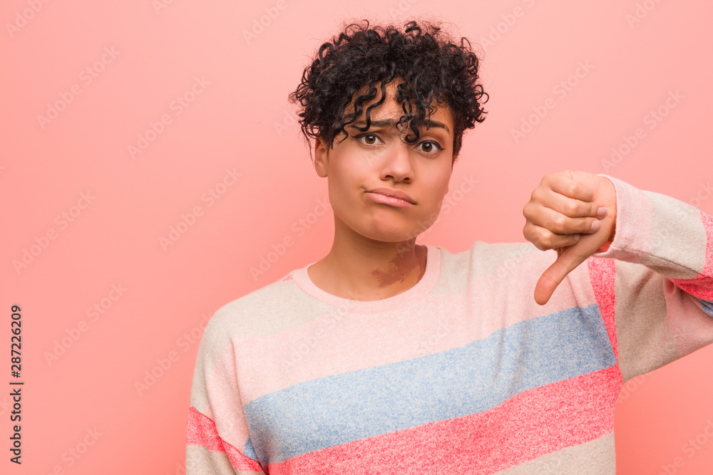 Young mixed african american teenager woman showing a dislike gesture, thumbs down. Disagreement concept. Young mixed african american teenager woman showing a dislike gesture, thumbs down. Disagreement concept.