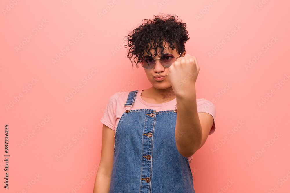 Young mixed african american teenager woman showing fist to camera, aggressive facial expression. Young mixed african american teenager woman showing fist to camera, aggressive facial expression.