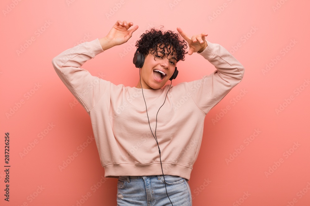 Young african american woman with a birthmark dancing and listening to music with a headphone - obrazy, fototapety, plakaty 