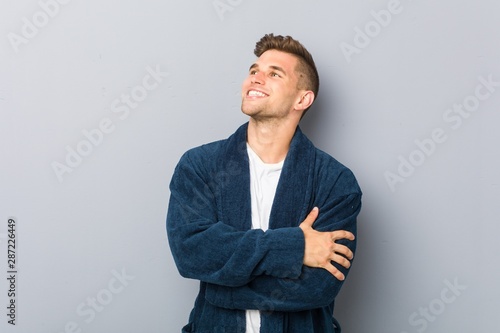 Young caucasian man wearing pajama smiling confident with crossed arms.